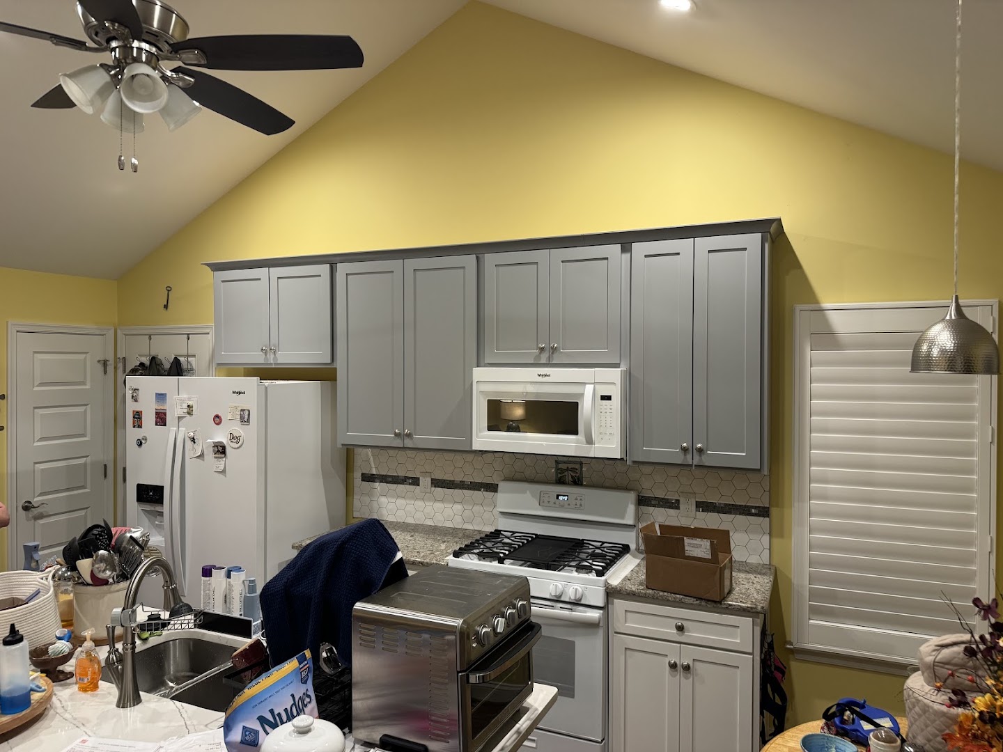 Kitchen with gray upper cabinets, white lower cabinets, and a tiled backsplash
