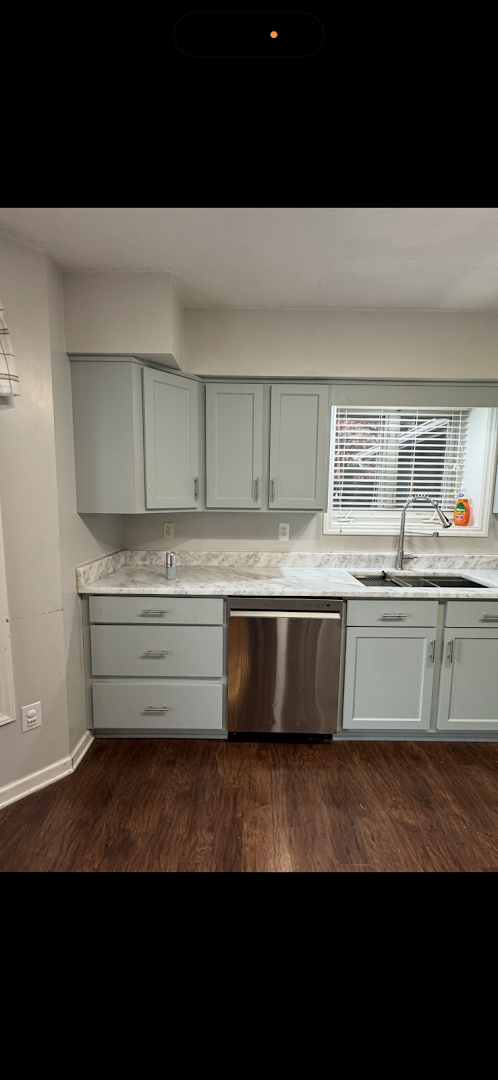 Light gray kitchen cabinets with a marble-look countertop and dishwasher