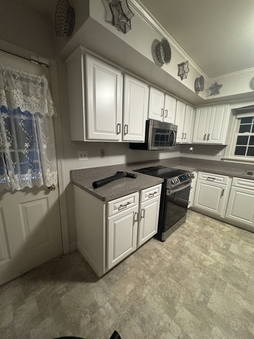 White kitchen cabinets and gray countertops viewed from the entry door