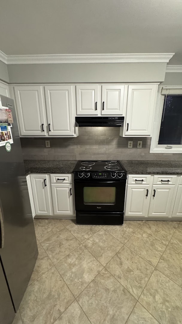 White kitchen cabinets with a black range and gray backsplash