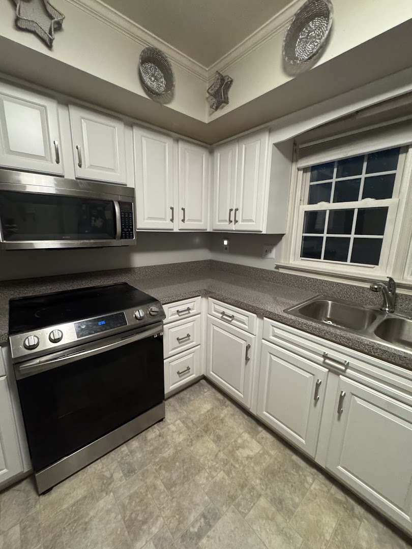 White shaker-style kitchen cabinets with a stainless steel range and sink