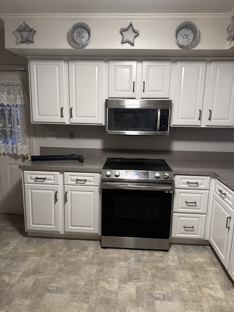 White kitchen cabinets surrounding a stainless steel range and microwave