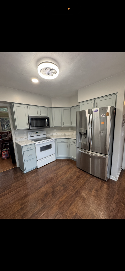 Light gray kitchen cabinets with white appliances and wood flooring