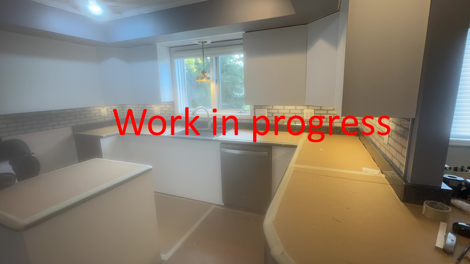 Kitchen renovation in progress with newly installed white cabinetry and backsplash