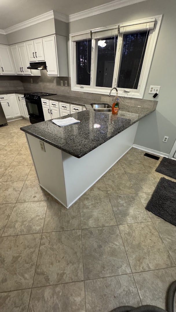 White kitchen cabinetry with a granite island and sink