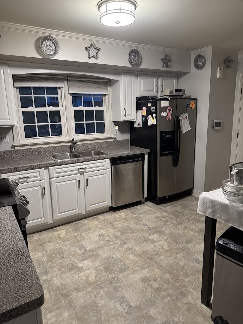 White kitchen cabinetry with a sink, dishwasher, and refrigerator surround