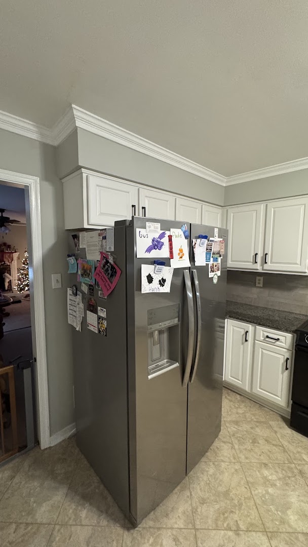 White kitchen cabinets surrounding a stainless steel refrigerator
