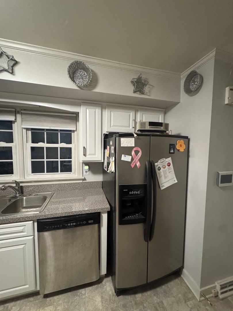 White kitchen cabinets beside a stainless steel refrigerator and dishwasher