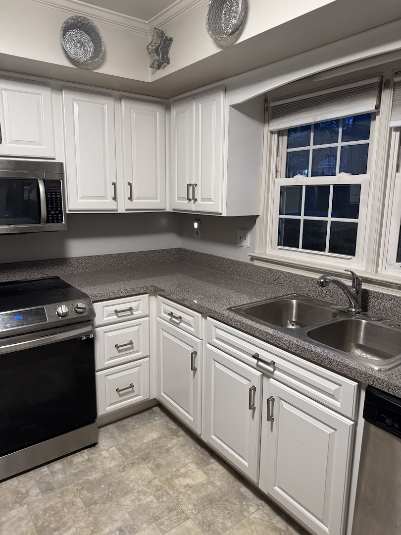 White shaker-style kitchen cabinets with updated hardware and a double sink